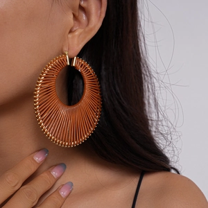 Close-up of bohemian brown woven hoop earrings with golden bead edges on a female model