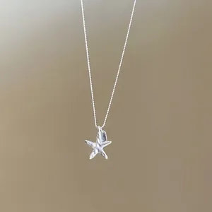 Detailed macro view of silver starfish pendant with LUCY tag on a delicate ball chain