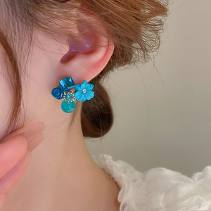 Close-up of blue cat eye stone flower earrings with crystals on a female model