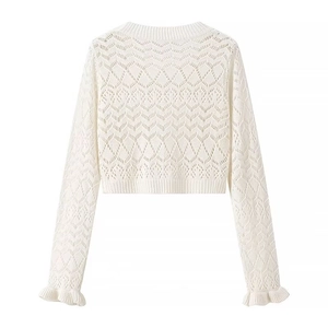 Detail of white hollow-out knit crop top showing crochet texture and ruffle hem edges