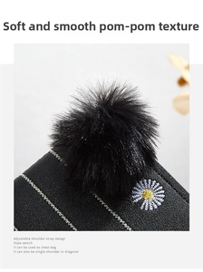 Macro shot of embroidered daisy pattern and fluffy black faux fur ball on a texture purse