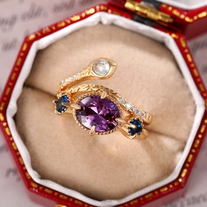 Artistic gold snake ring with oval purple gemstone and blue accents in red jewelry box