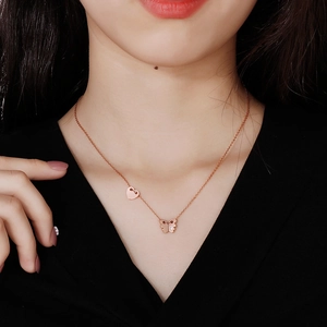 Close-up of rose gold butterfly and heart pendant necklace on a model's neck
