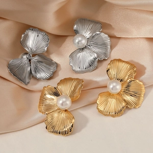 Elegant gold and silver floral pearl earrings displayed on soft beige silk fabric