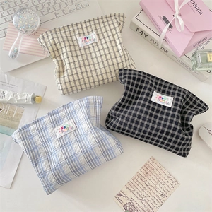 Detailed flat lay of checkered cosmetic bags in cream, blue, and black fabric styles