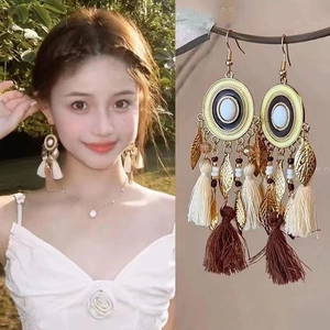 Bohemian feather tassel earrings with beads and metal charms shown on model and close-up