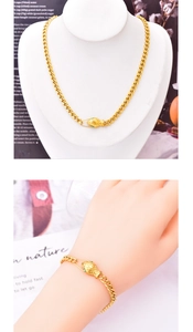 Detailed view of gold snake-head necklace and bracelet set with green accents