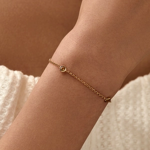 Pulsera minimalista de cadena dorada con dos piedras ámbar lucida en la muñeca de una modelo