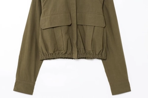Detail of army green utility jacket featuring large cargo pockets and elastic waist hem