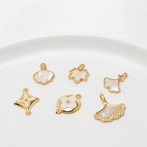 Macro shot of assorted ginkgo leaf and clover charms with shell inlay and cubic zirconia