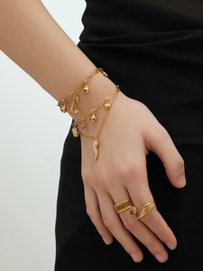 Gros plan de bracelets multicouches et bagues en acier doré avec détails en zircon