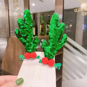 Detail of green sequin reindeer antler hair clips with red pompom on a metal duckbill base