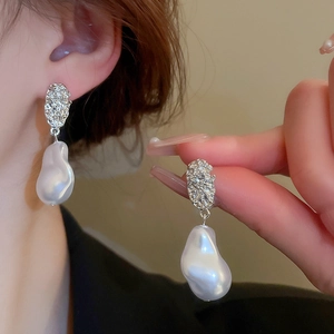 Macro detail of silver textured metal stud with white irregular drop pearl earring