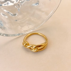 Vista dettagliata di un anello minimalista in acciaio inossidabile dorato con design a nodo.