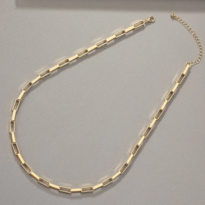 Minimalist golden paperclip chain necklace with lobster clasp on grey textured background