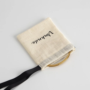 Detail of a gold crystal-embellished bangle placed on a cream cotton drawstring pouch