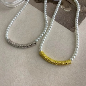 Detail of white pearl necklaces with textured gold and silver metal curved accents