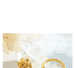 Detail of minimalist gold-plated rings on white lace with decorative dried petals