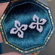 Detailed close-up of fleur-de-lis pave earrings in a luxury green velvet jewelry box