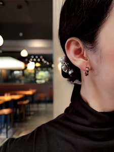 Close-up of S925 silver earring with black and gold animal pattern on model's ear
