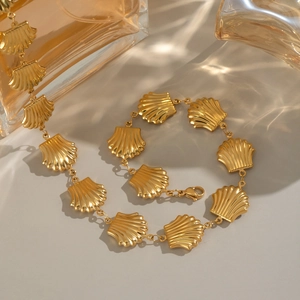 Detailed close-up of gold shell pendant necklace with lobster clasp on a polished surface