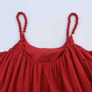 Détail de robe de plage rouge avec bretelles perlées et texture plissée du décolleté