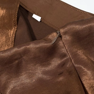Détail d'une jupe en satin marron avec fermeture éclair invisible et coutures précises