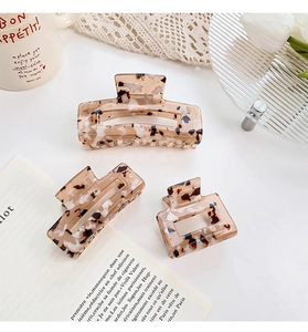 Close-up of three leopard print claw clips in varying sizes on a minimalist background