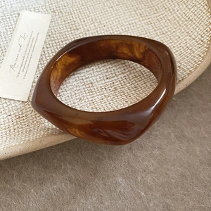 Macro shot of an amber resin geometric bracelet with marble pattern on a ceramic plate