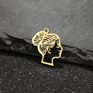 Close-up of golden cartoon girl pendant with hair bun silhouette on dark rock texture