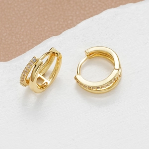 Golden double-layer geometric hoop earrings with zircon accents on a modern stone backdrop