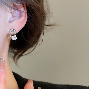 Detailed close-up of a silver geometric hoop earring with a sparkling round zircon stone