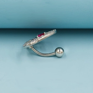 Macro side view of curved silver navel ring with red center stone and white crystals