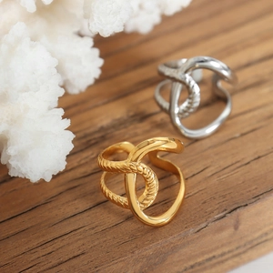 Irregular twisted cross rings in gold and silver steel with polished rope texture