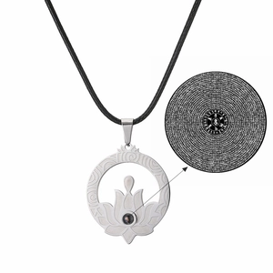 Detail of silver lotus pendant featuring a micro-carved sutra stone and black woven cord