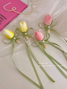 Detail of tulip-shaped hair clips with long ribbons and elegant pearls on silk fabric