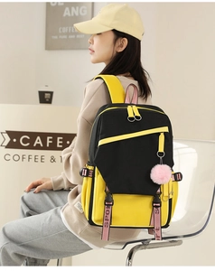 Detail of yellow and black nylon backpack with pink sporty straps and plush pendant charm