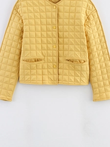 Détail d'une veste matelassée jaune chaud avec boutons-pression et coutures à carreaux