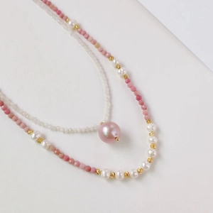 Detailed macro shot of pink natural stone beads and white pearls on a double-layer necklace