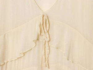 Detail of V-neckline with ties and ruffle trim on cream chiffon midi dress