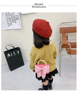 Girl wearing a pink tweed crossbody bag with a large bow and pearl handle in a trendy look