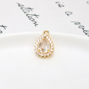 Macro detail of a pear-shaped glass pendant with gold plating and cubic zirconia inlay