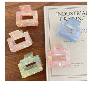 Detailed view of colorful iridescent square hair claws on a vintage book surface