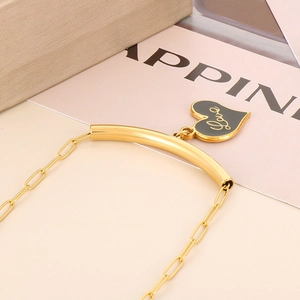 Detail view of a gold heart pendant featuring a black center with Love script engraving