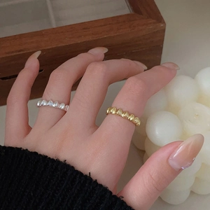 Close-up of minimalist gold and silver wavy texture rings worn in a warm lifestyle setting