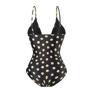 Detail of swimsuit featuring gold polka dot print and beaded strap accents