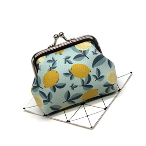 Detailed close-up of light blue fabric coin purse with lemon pattern and silver metal clasp