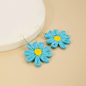 Détail macro de boucles d'oreilles marguerites bleues tressées avec crochets dorés