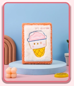 Detalle de cuaderno de peluche naranja con bordado de helado rosa y suave textura