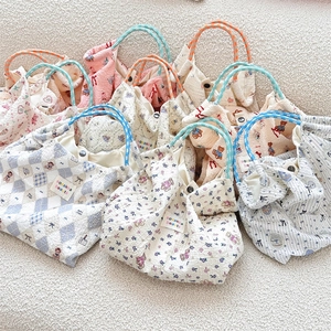 Detail of seersucker tote bag with cute cartoon prints and woven handles on a soft rug